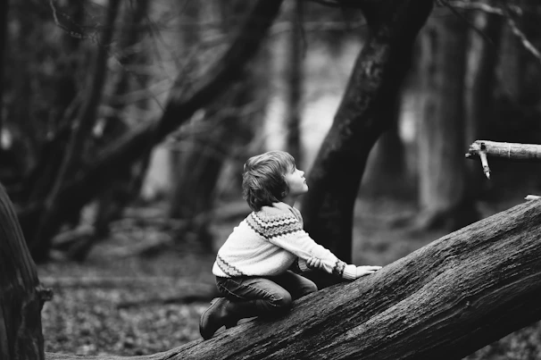 Child in a cozy beige sweater playing in a softly blurred natural setting.