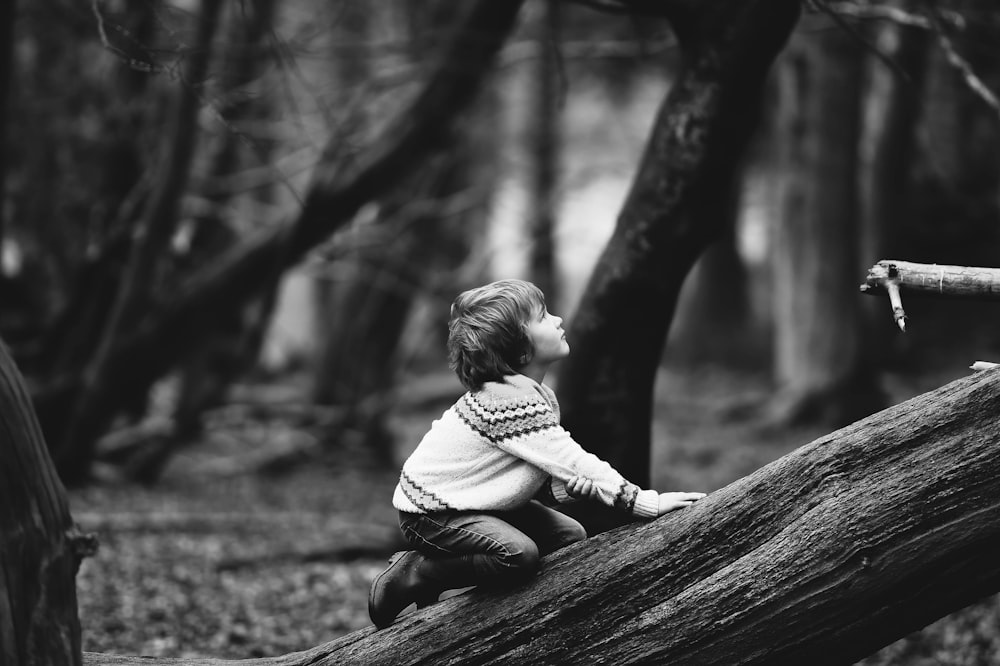 boy climbing fallen tree