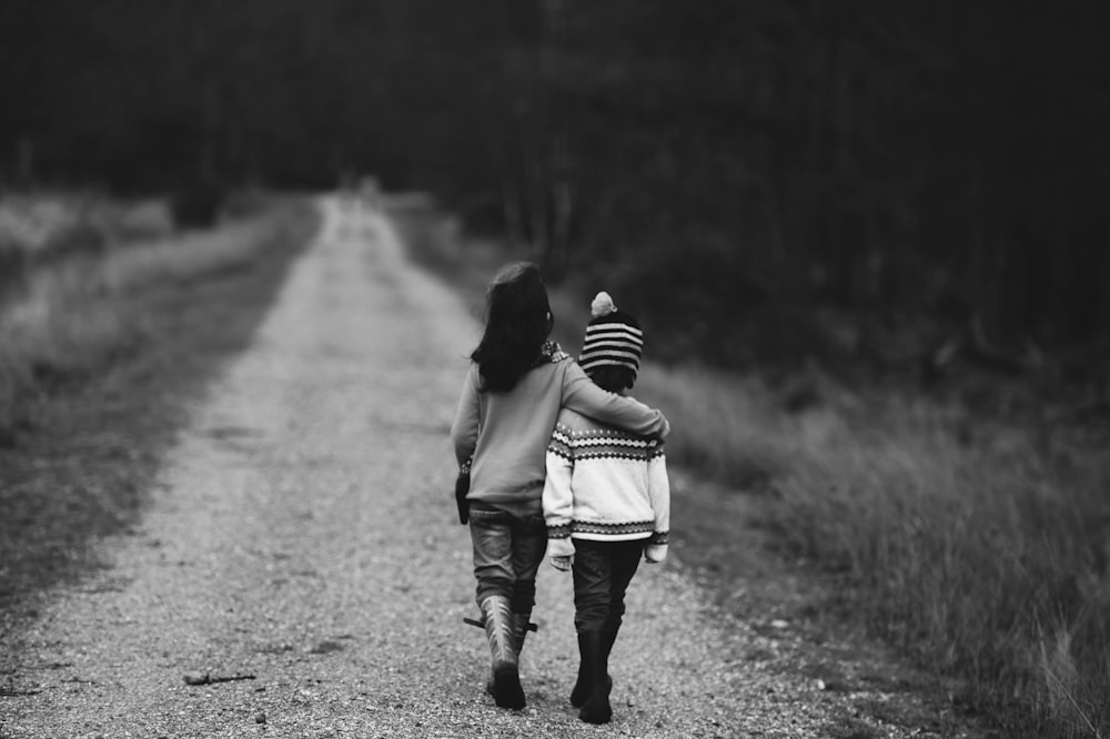 fotografia em tons de cinza de crianças andando na estrada