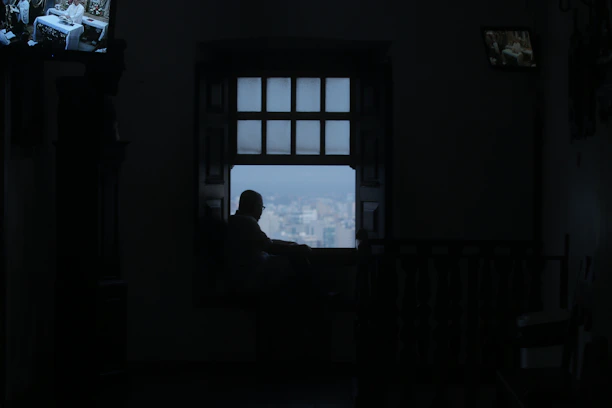 Silhouette of a thoughtful woman gazing into a dimly lit room with digital code flowing softly around her.
