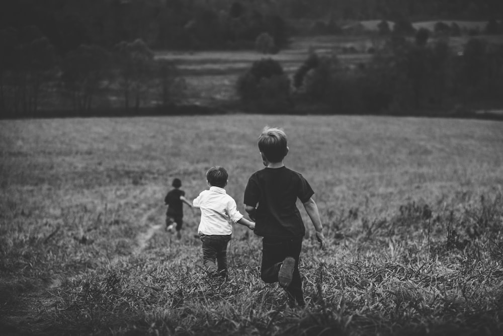 three boys running on field