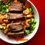 Artfully plated Asian fusion dish featuring grilled meat and fresh vegetables.