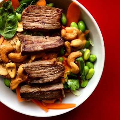 Artfully plated Asian fusion dish featuring grilled meat and fresh vegetables.