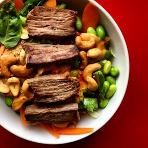Artfully plated Asian fusion dish with grilled meat and fresh vegetables.