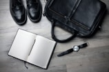 A worn pair of boots resting beside an open journal and pen on a wooden bench.