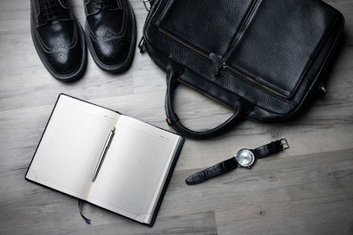 A stylish briefcase placed next to a laptop and notebook on a clean desk.