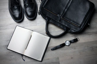 A stylish briefcase placed next to a laptop and notebook on a clean desk.