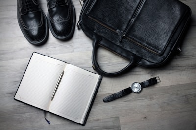 A neat portfolio book open on a wooden desk with notes and pens.