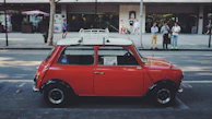 A bright red compact car perfect for city driving, parked near a bustling street.