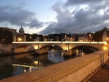 High-contrast shot of an ancient stone bridge over a dark river at dusk.