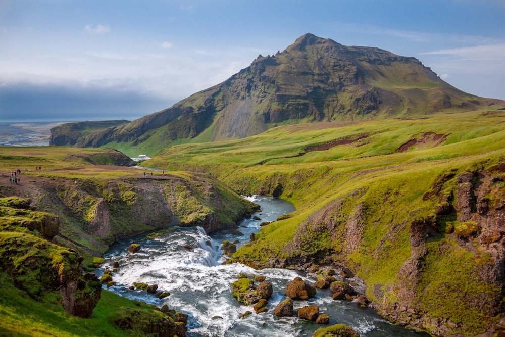 photo of river and green grass covered moutain