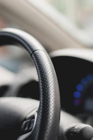 Close-up of a mach1's hand-stitched leather steering wheel with dashboard lights glowing.