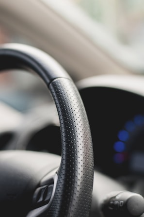 A steering wheel with a blurred background, showcasing speed.