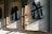 Three black jackets are displayed in wooden frames, with sunlight casting shadows across the scene.