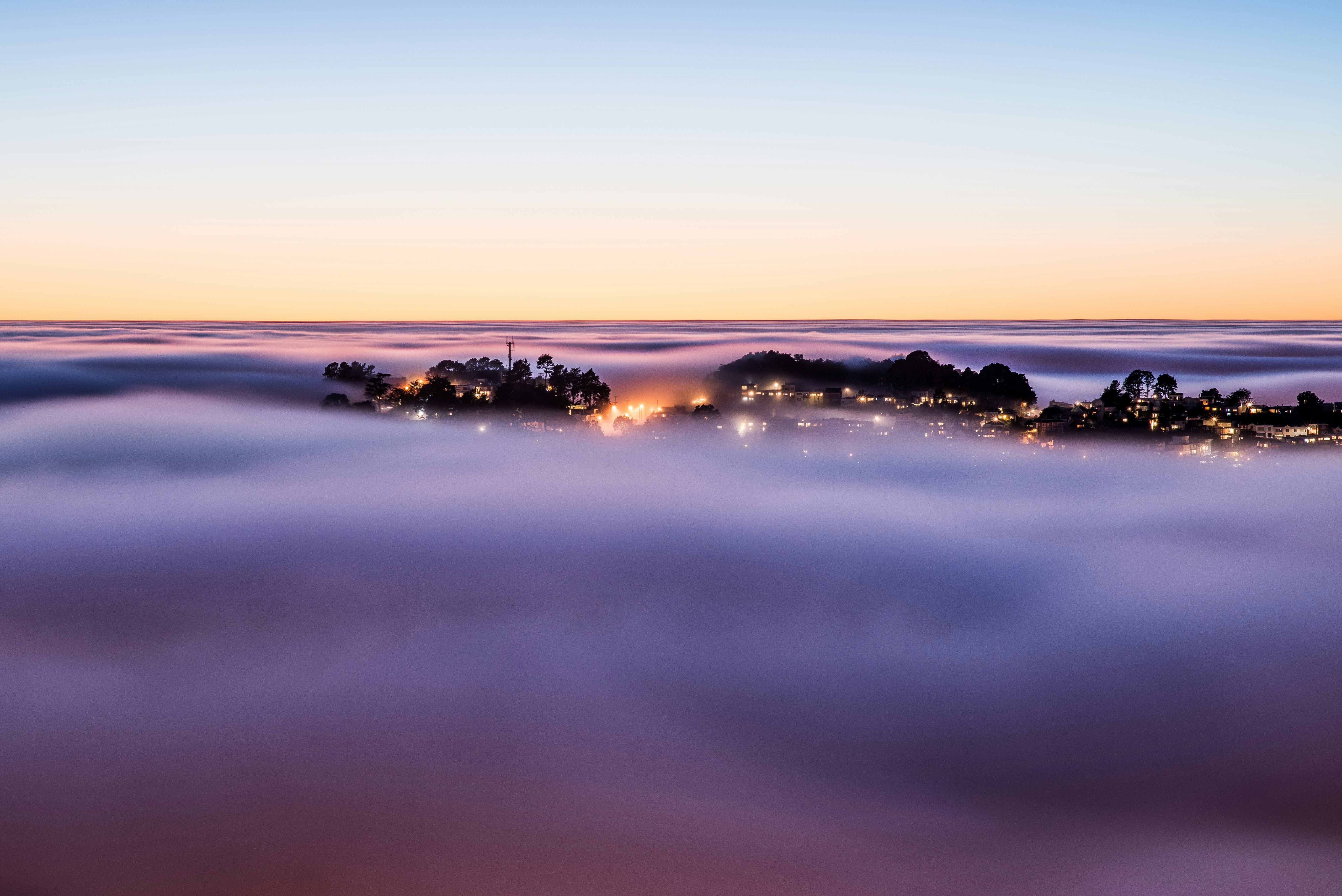 An image of a thick mist, through which a town seems to be peeking. Photo by John Chavez.