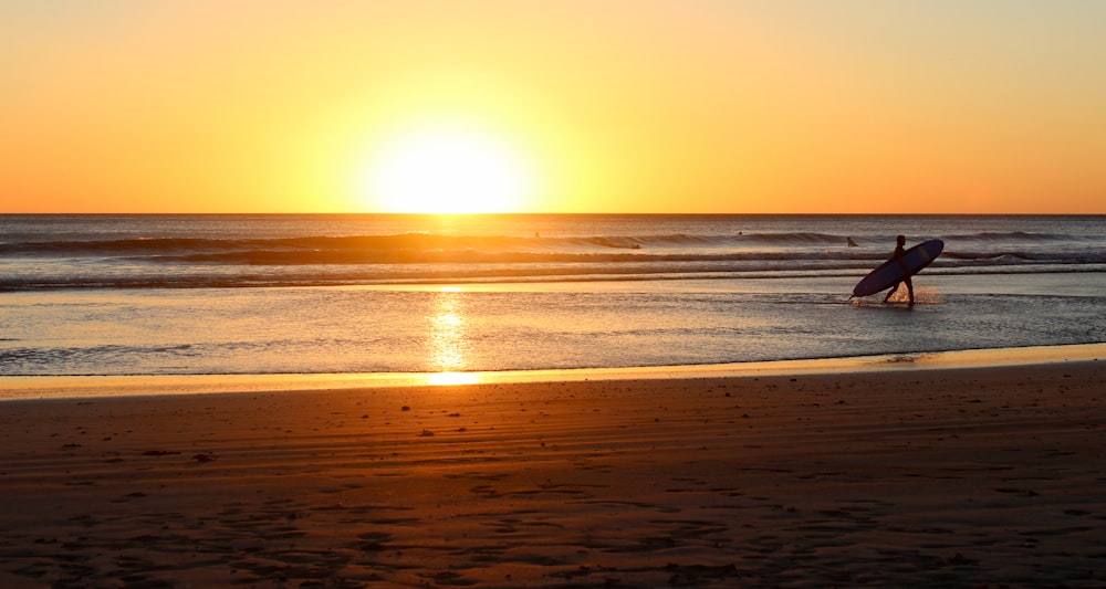 person walking on body of water while holding surfboard