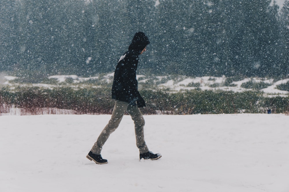 man walking on snow-covered road