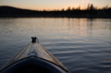 Sunset over a peaceful lake with kayakers enjoying the calm water and distant mountains.