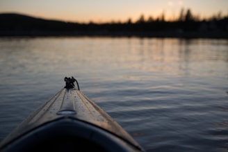 A vibrant sunset casting golden hues over calm lake waters with a kayak silhouette