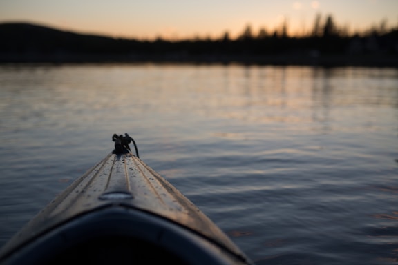 A serene lakeside scene at sunset with an infallible kayak resting on the shore.