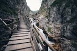 brown wooden bridge in the middle of two mountain