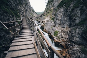 brown wooden bridge in the middle of two mountain