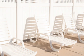 A sleek plastic outdoor dining chair set around a sunlit patio table.
