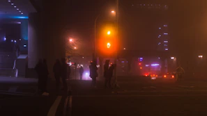 Urban textures illuminated by orange streetlights with volunteers moving through the misty night.