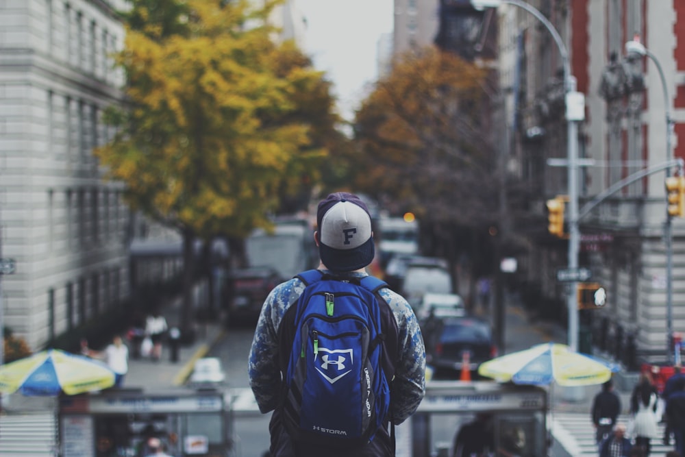 homem com mochila na rua em fotografia de foco raso