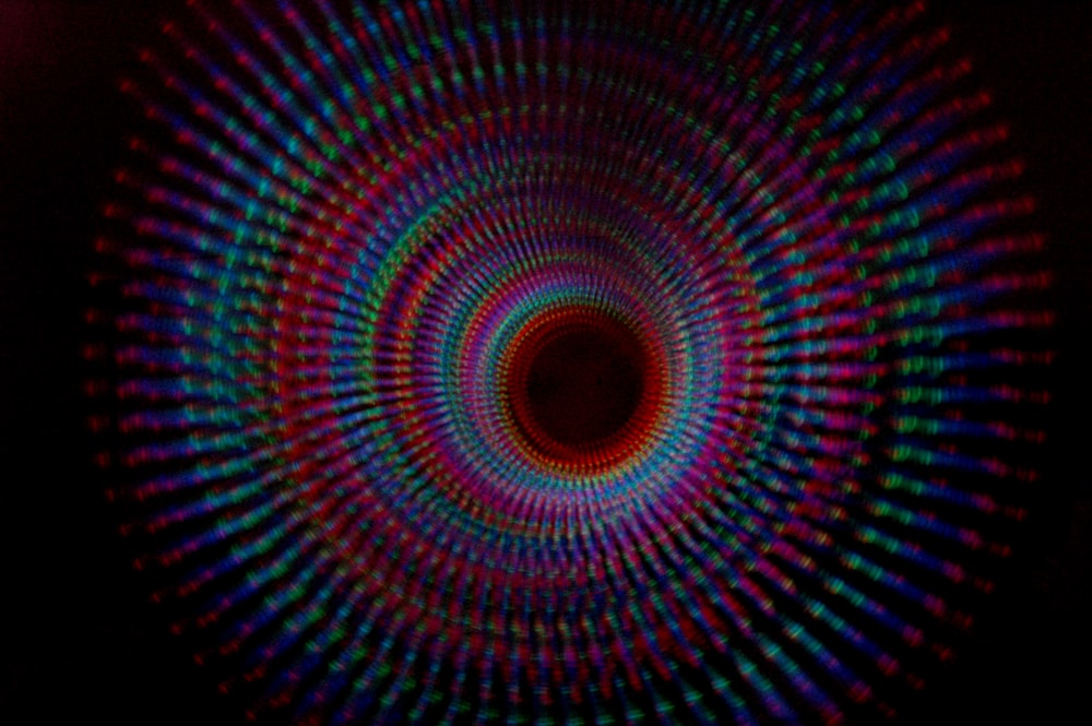 A spiral pattern of various color lights in a dark tunnel.