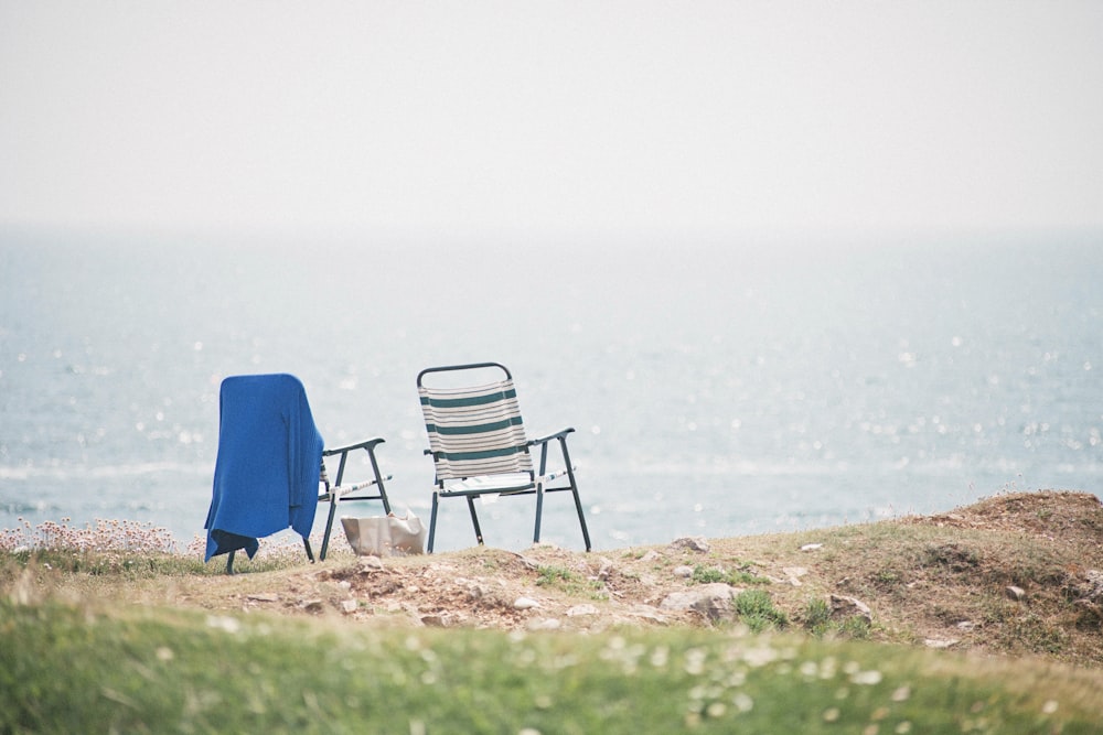 two gray folding armchairs near seashore