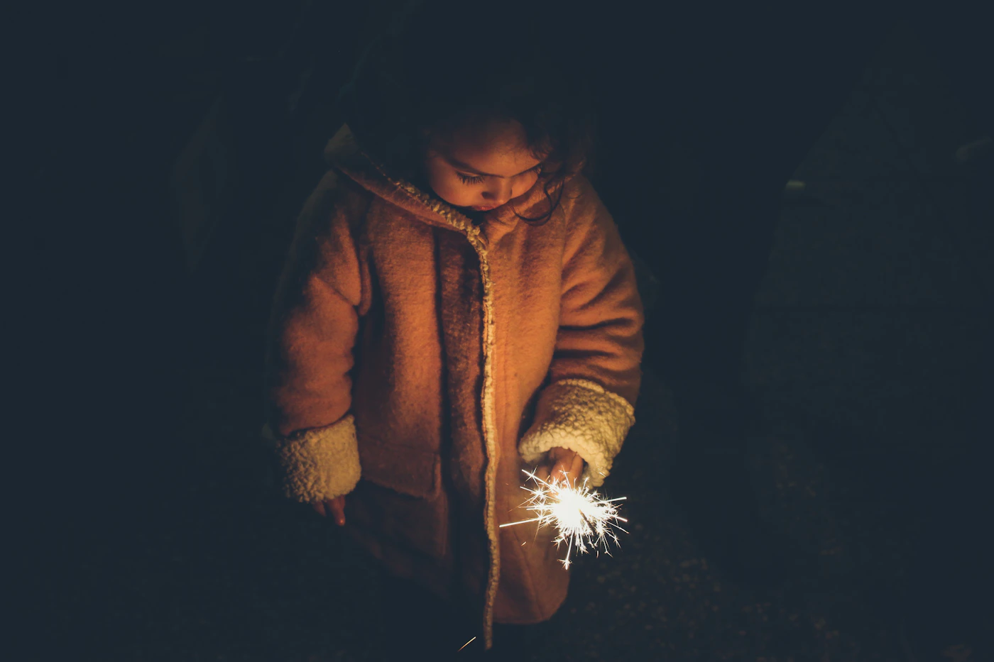 A child holding a sparkler, representing wonder and the younger self