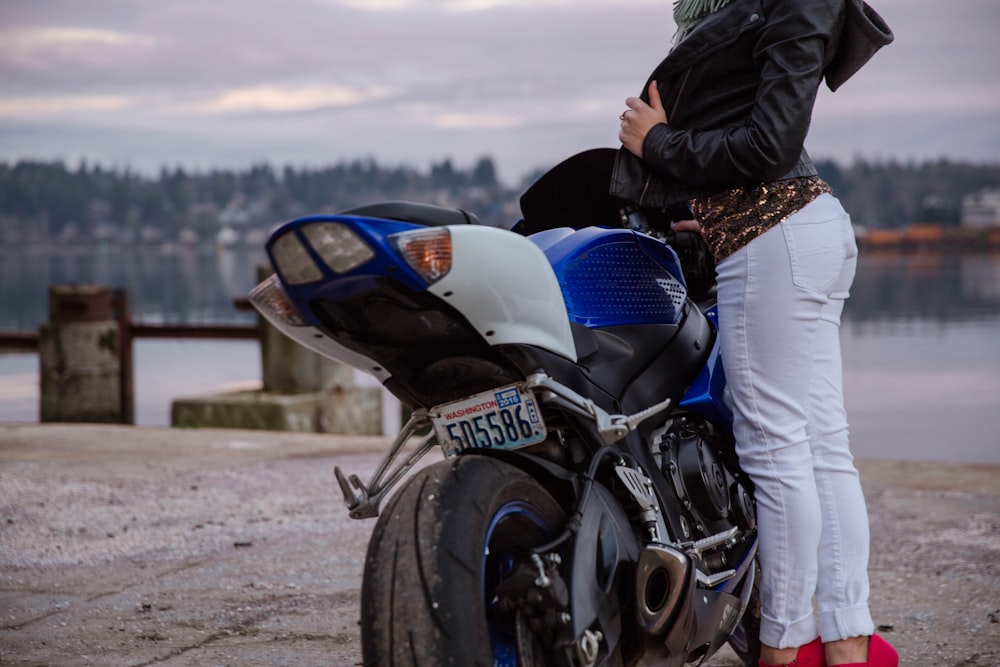 Mujer de pie frente a la motocicleta azul