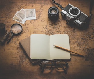 flat ray photography of book, pencil, camera, and with lens