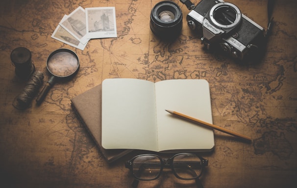 flat ray photography of book, pencil, camera, and with lens