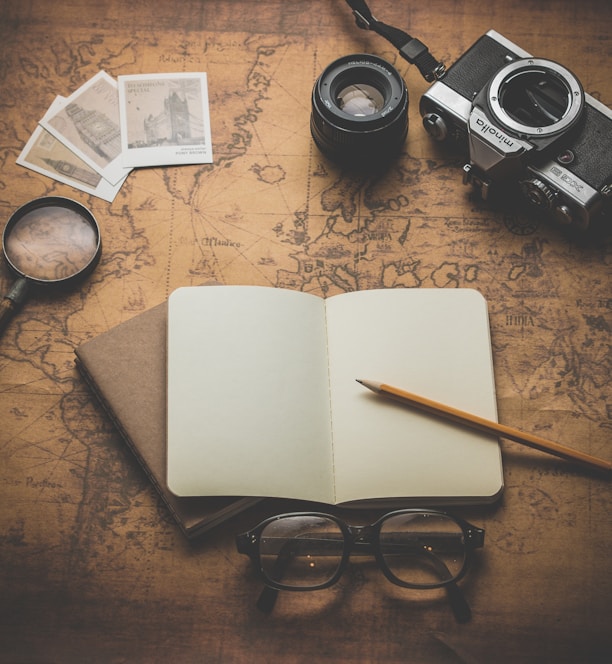 flat ray photography of book, pencil, camera, and with lens