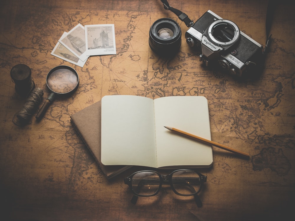 Photographie à rayons plats du livre, du crayon, de l’appareil photo et de l’objectif