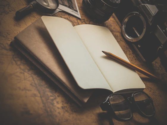 Handcrafted notebook resting on a rustic wooden table with travel maps and a pen nearby, evoking a journey of creativity.