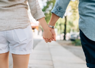 man and woman holding hands together in walkway during daytime