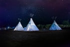 three white teepee tents under starry sky
