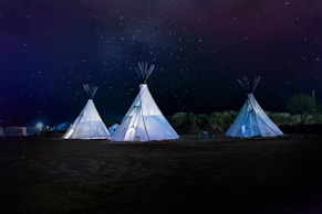 three white teepee tents under starry sky