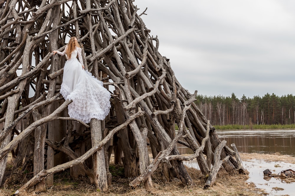 woman in white dress on piled wood logs