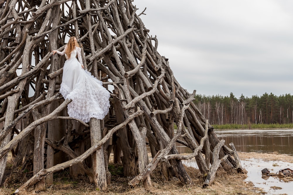 Mujer en vestido blanco sobre troncos de madera apilados