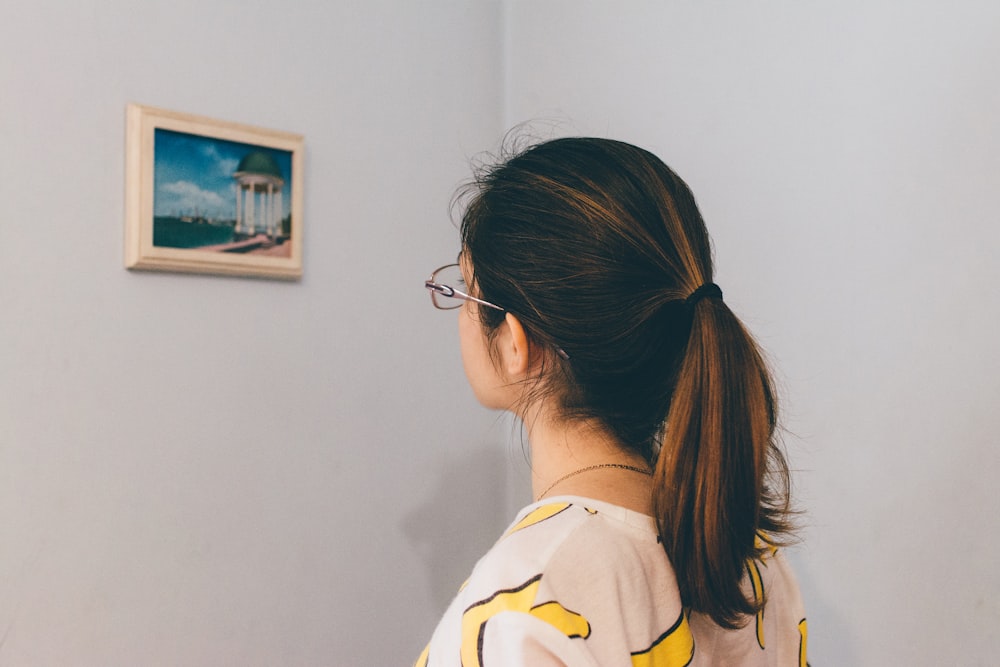 Mujer mirando la foto en la pared dentro de la habitación