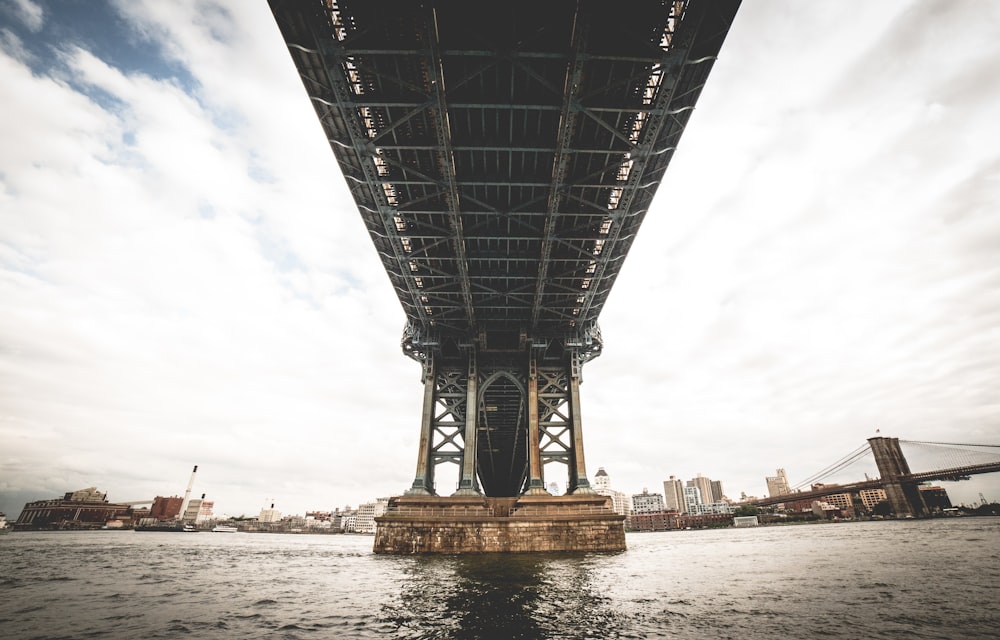 grey steel bridge over sea under grey and blue sky