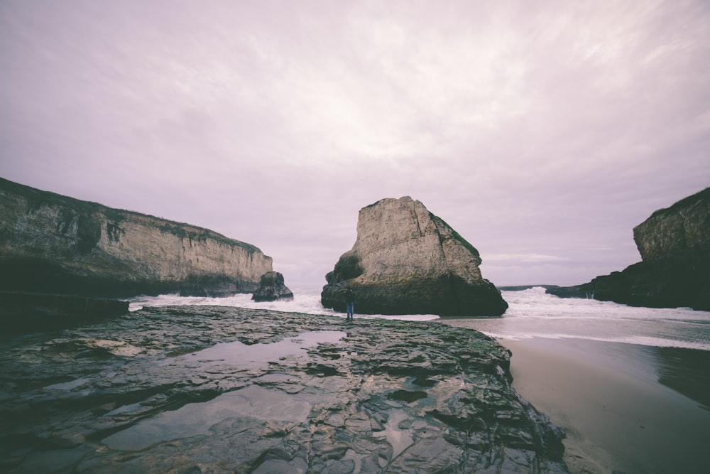 Foto de paisaje de una isla rocosa blanca y gris cerca del océano bajo el cielo nublado