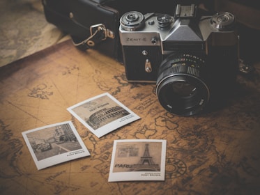 black and grey DSLR camera near several photos on brown map