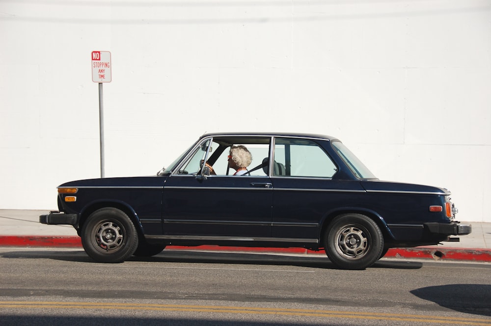 person driving black coupe during daytime