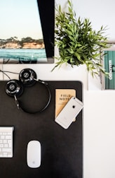 A neat workspace with a laptop, headphones, and a notebook showing digital planning.