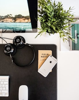 black headphones beside space gray iPhone on brown table